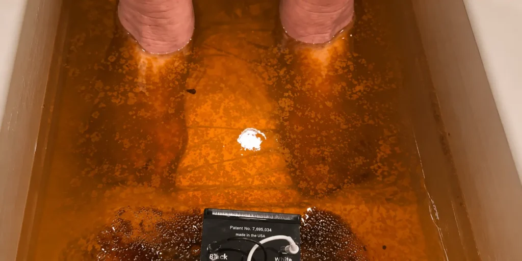 Feet soaking in orange-brown bathtub water